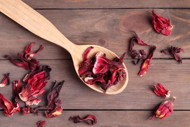 Spoon with dry hibiscus tea on wooden table, flat lay