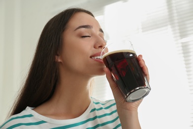 Beautiful woman with cold kvass indoors. Traditional Russian summer drink