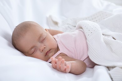 Photo of Cute little baby in bodysuit sleeping on bed