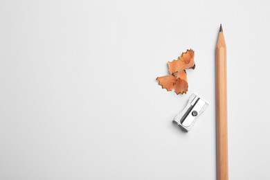 Photo of Graphite pencil, sharpener and shavings on white background, flat lay. Space for text