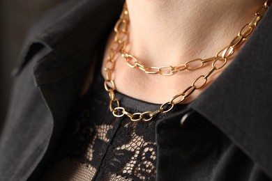 Photo of Woman wearing stylish metal chain, closeup. Luxury jewelry