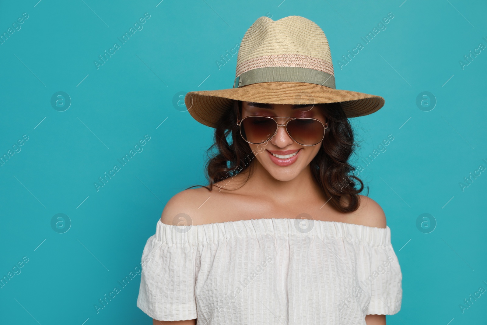 Photo of Beautiful young woman with straw hat and stylish sunglasses on light blue background