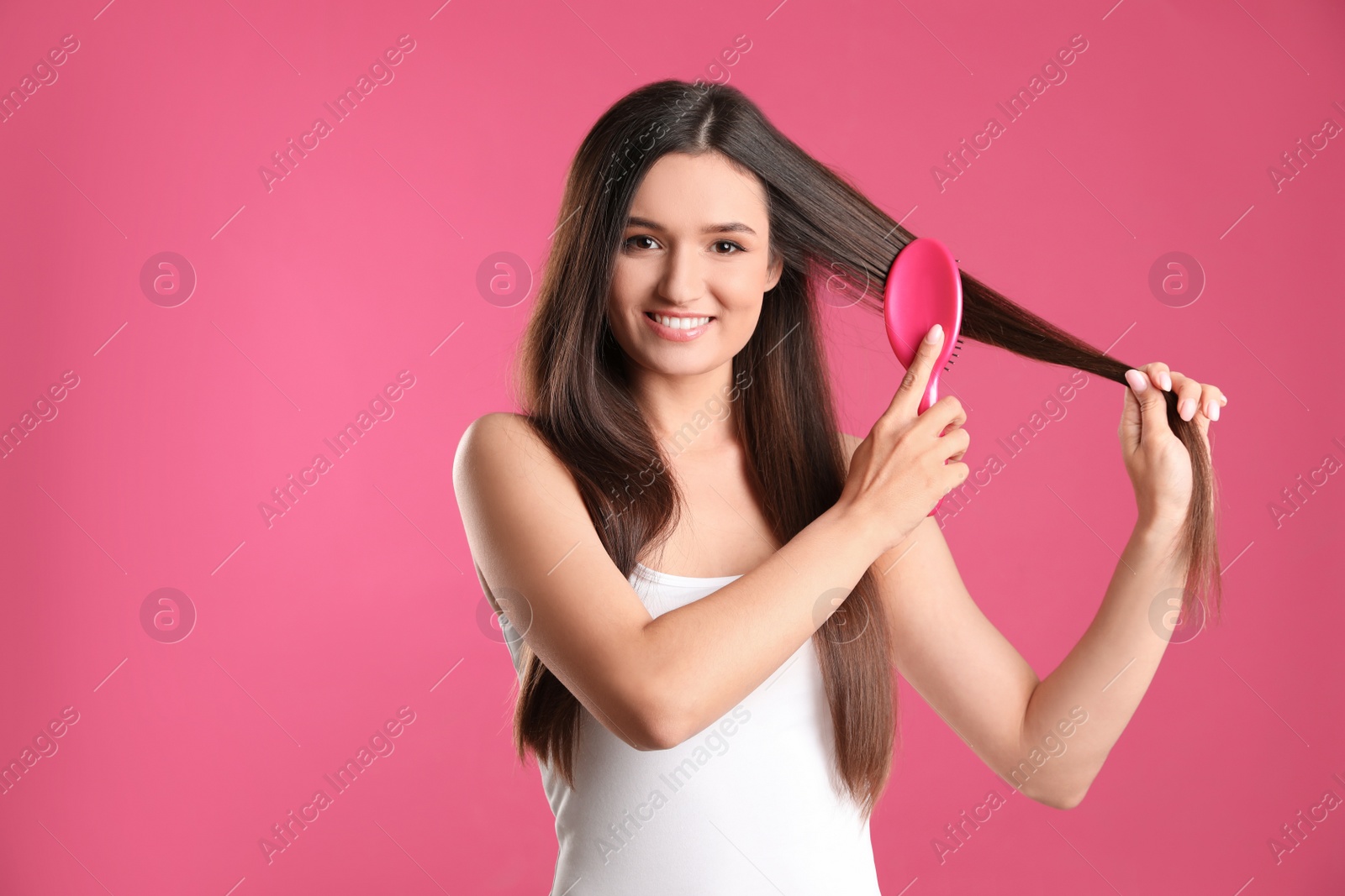 Photo of Beautiful smiling young woman with hair brush on color background