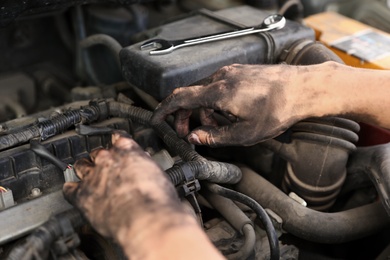 Dirty mechanic fixing car, closeup of hands