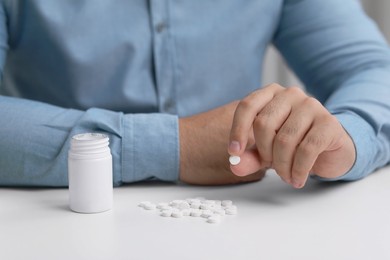 Photo of Man holding antidepressant pill at white table, closeup