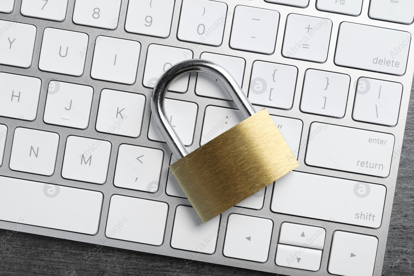 Photo of Cyber security. Metal padlock and keyboard on grey table, top view