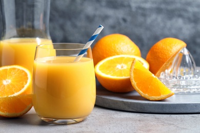 Glass of orange juice and fresh fruits on grey table, closeup