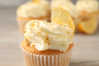 Photo of Tasty cupcake with cream, zest and lemon slice on table, closeup