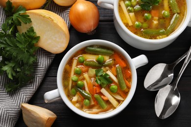 Photo of Bowls of tasty turnip soup and ingredients on dark wooden table, flat lay