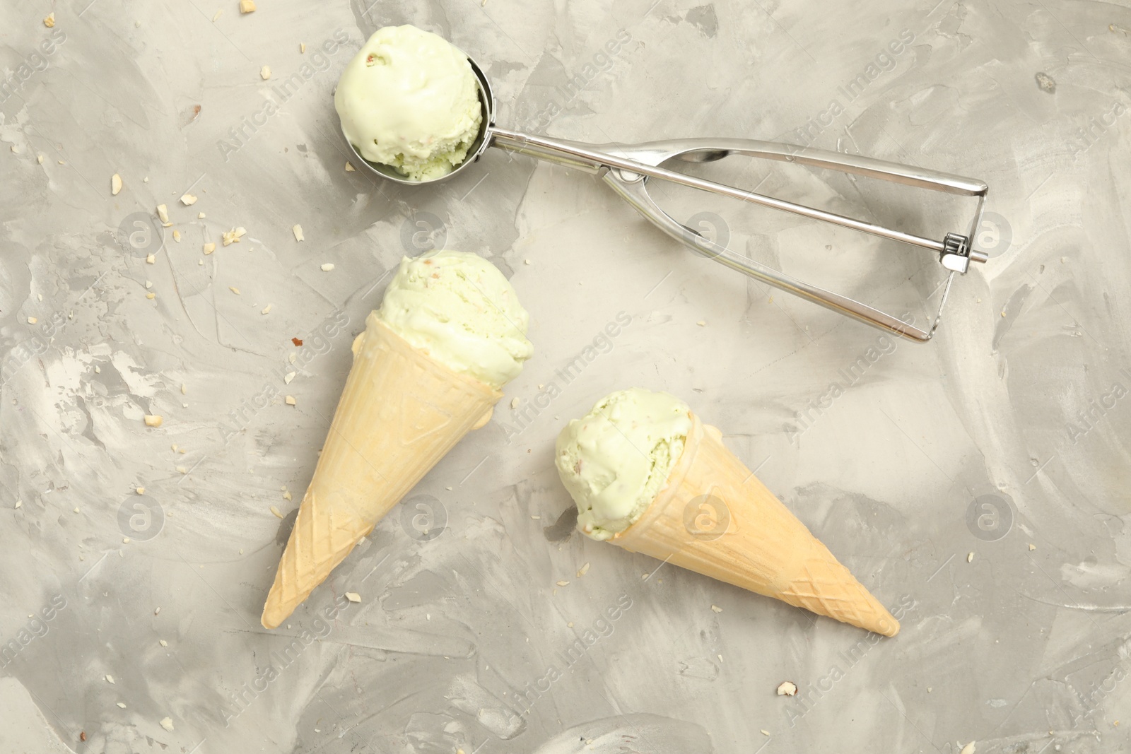 Photo of Delicious pistachio ice cream in wafer cones on light grey table, flat lay