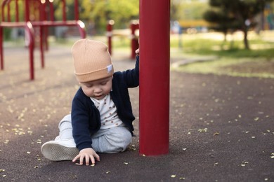 Photo of Little baby sitting on playground in park