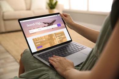 Woman using laptop to book flight at home, closeup