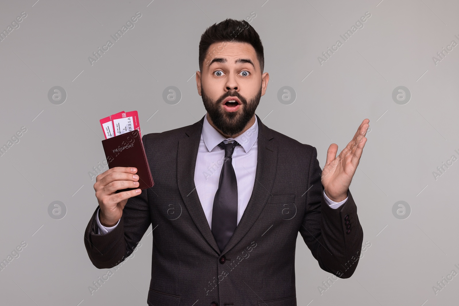 Photo of Surprised businessman with passport and tickets on grey background