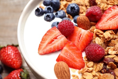 Photo of Tasty homemade granola served on wooden table, closeup. Healthy breakfast