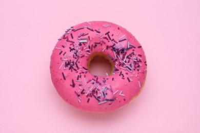 Photo of Glazed donut decorated with sprinkles on pink background, top view. Tasty confectionery