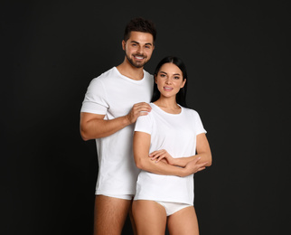 Photo of Young couple in white t-shirts and underwear on black background