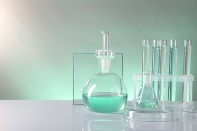 Photo of Laboratory analysis. Different glassware on table against color background, space for text