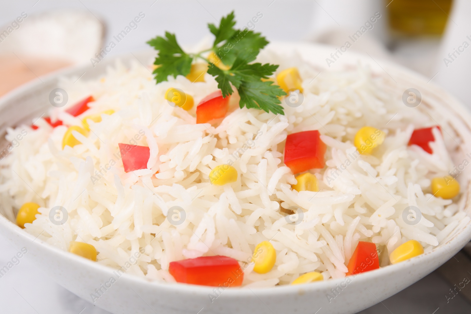 Photo of Bowl of delicious rice with vegetables and parsley on table, closeup