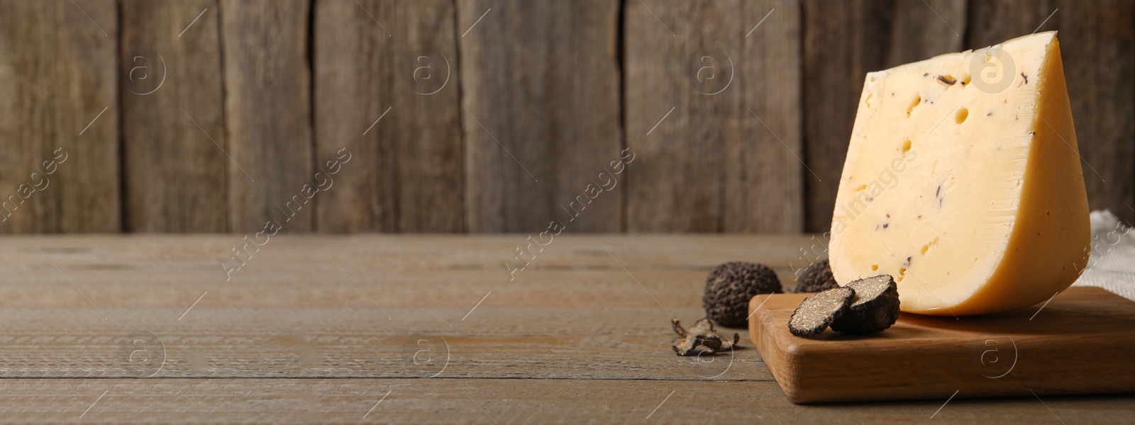 Image of Delicious cheese and fresh black truffles on wooden table, space for text. Banner design