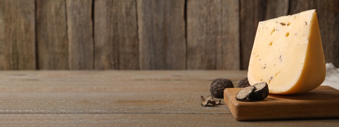 Image of Delicious cheese and fresh black truffles on wooden table, space for text. Banner design