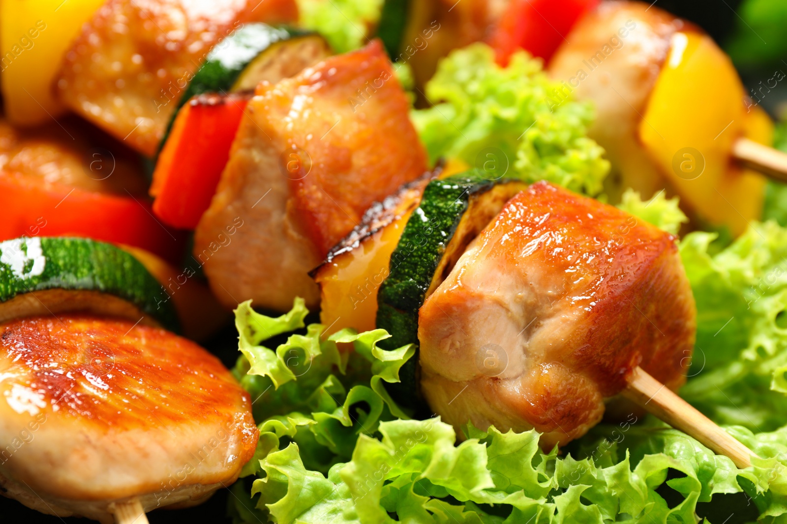 Photo of Delicious chicken shish kebabs with vegetables  as background, closeup