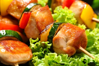 Photo of Delicious chicken shish kebabs with vegetables  as background, closeup