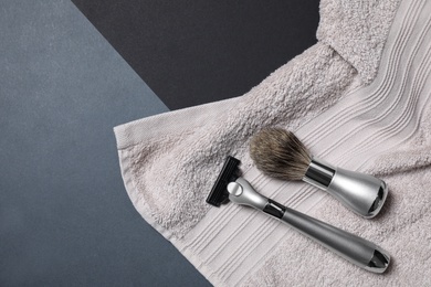 Photo of Razor, brush and towel for shaving on dark background, flat lay