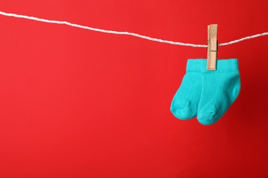 Photo of Cute child socks on laundry line against color background. Space for text