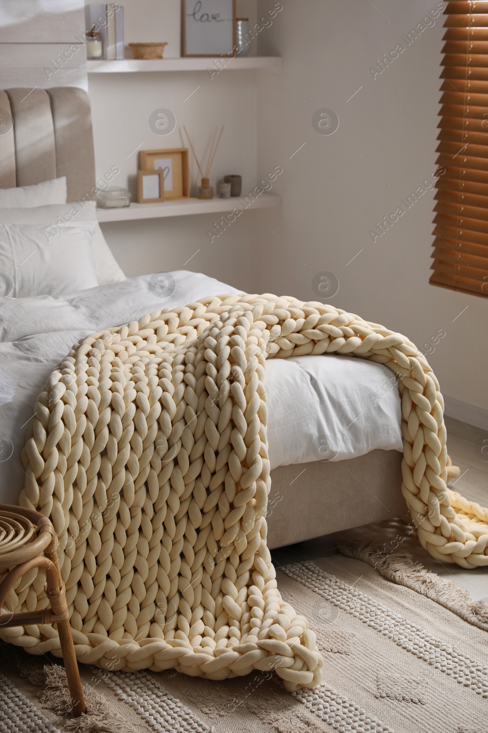 Photo of Soft chunky knit blanket on bed in stylish room interior