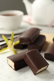 Photo of Glazed curd cheese bars, vanilla pods and flower on table, closeup