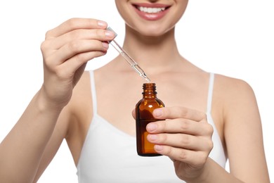 Young woman with bottle of essential oil on white background, closeup