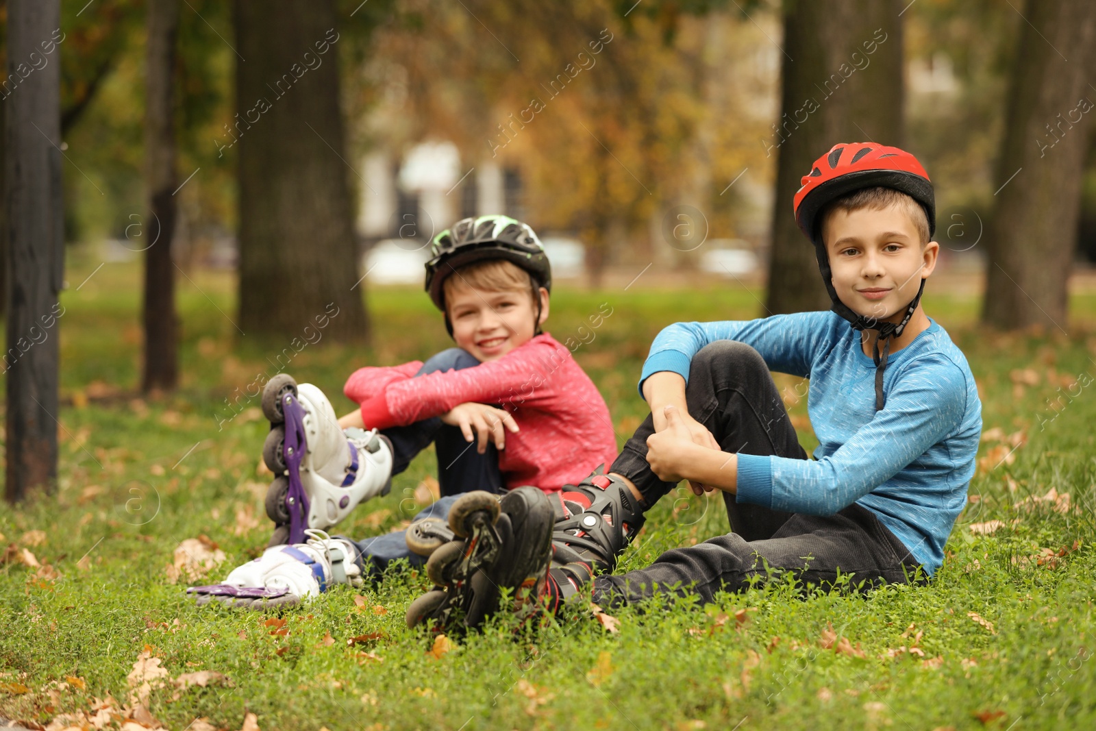 Photo of Cute roller skaters sitting on grass in park