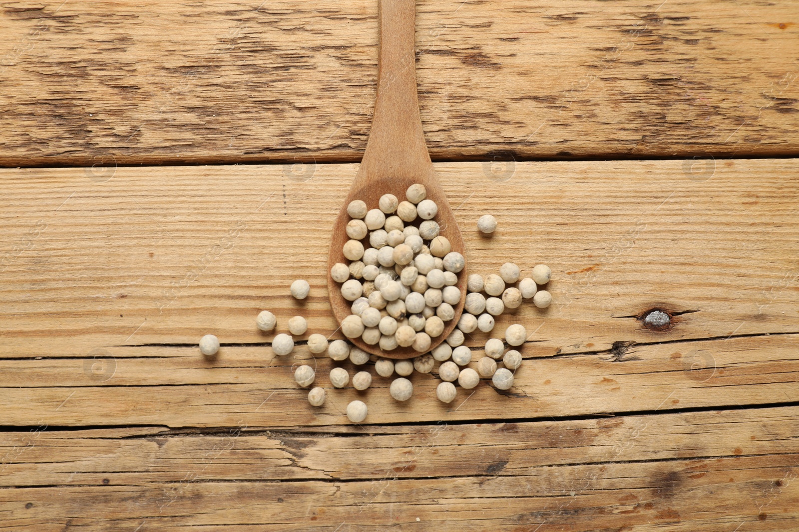 Photo of Aromatic spice. White pepper in spoon on wooden table, top view