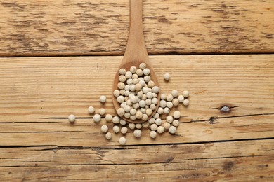 Photo of Aromatic spice. White pepper in spoon on wooden table, top view