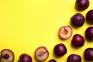 Delicious ripe plums on yellow background, flat lay. Space for text