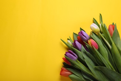 Bunch of beautiful tulips on yellow background, flat lay. Space for text