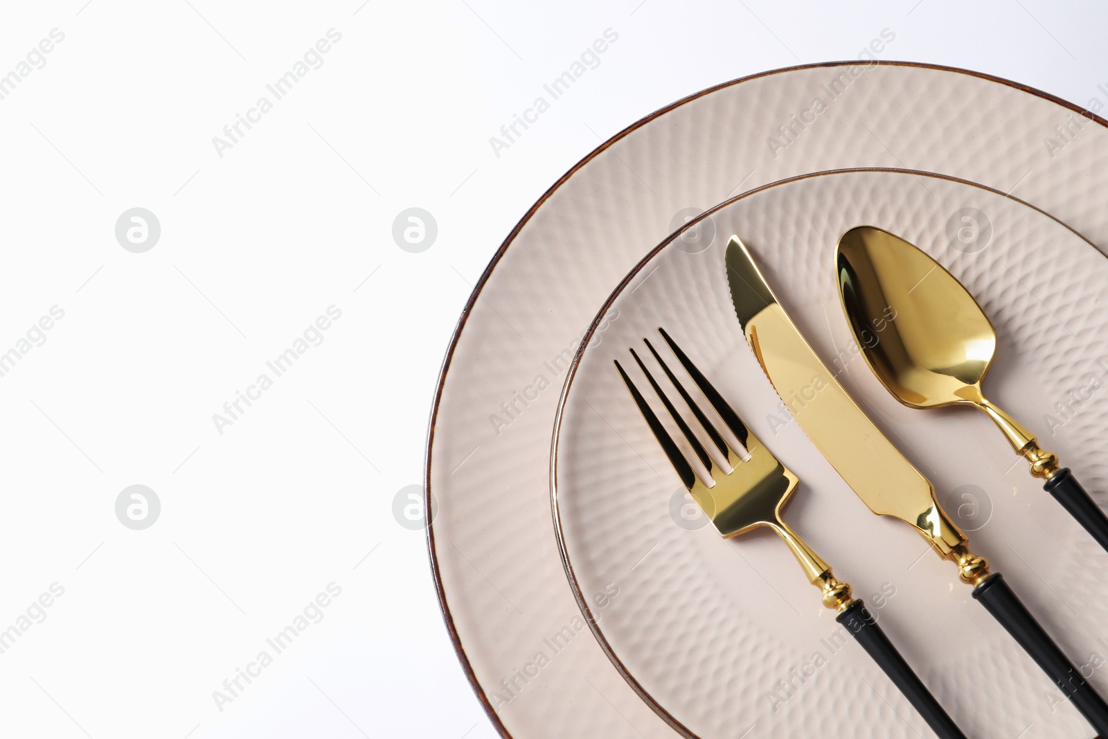 Stylish golden cutlery and plates on white background, top view. Space for text Photo of Stylish golden cutlery and plates on white background, top view. Space for text