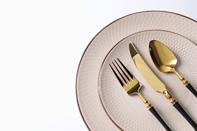 Photo of Stylish golden cutlery and plates on white background, top view. Space for text