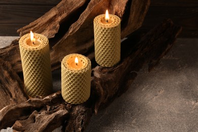 Photo of Beautiful burning beeswax candles on snag indoors
