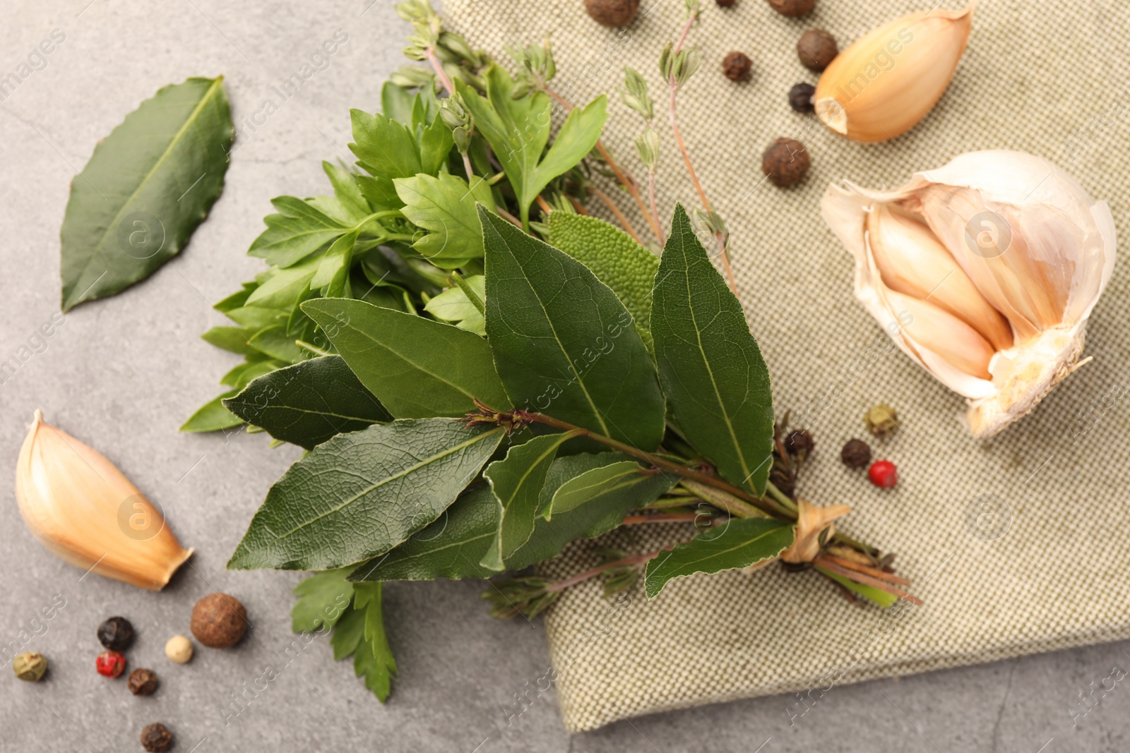 Photo of Aromatic fresh bay leaves, different herbs and spices on light gray table, flat lay