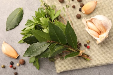 Aromatic fresh bay leaves, different herbs and spices on light gray table, flat lay