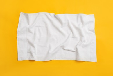 Photo of Crumpled white beach towel on yellow background, top view