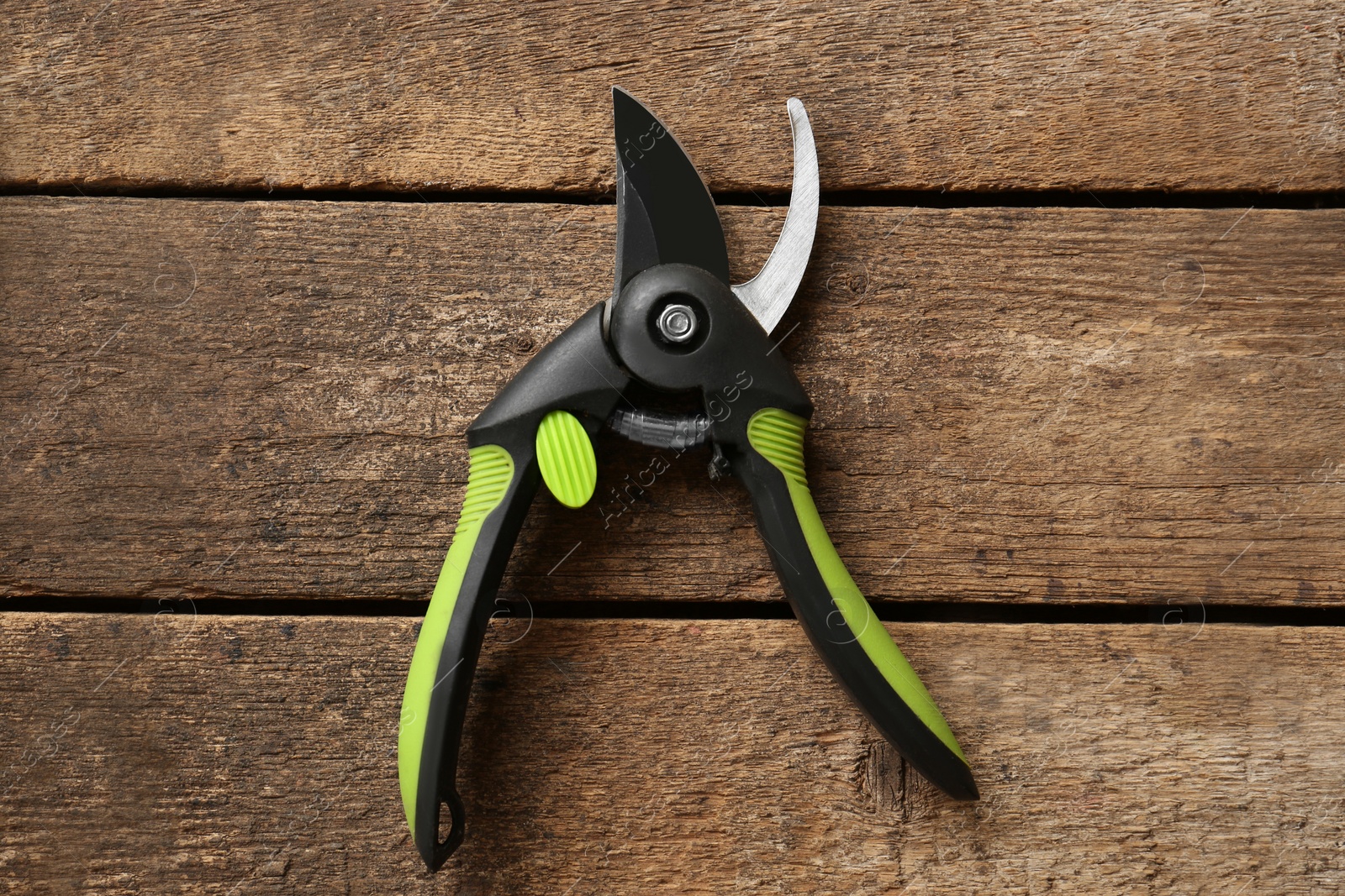 Photo of Secateur on wooden table, top view. Gardening tool