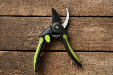 Photo of Secateur on wooden table, top view. Gardening tool