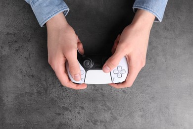 Photo of Man using wireless game controller at grey table, top view