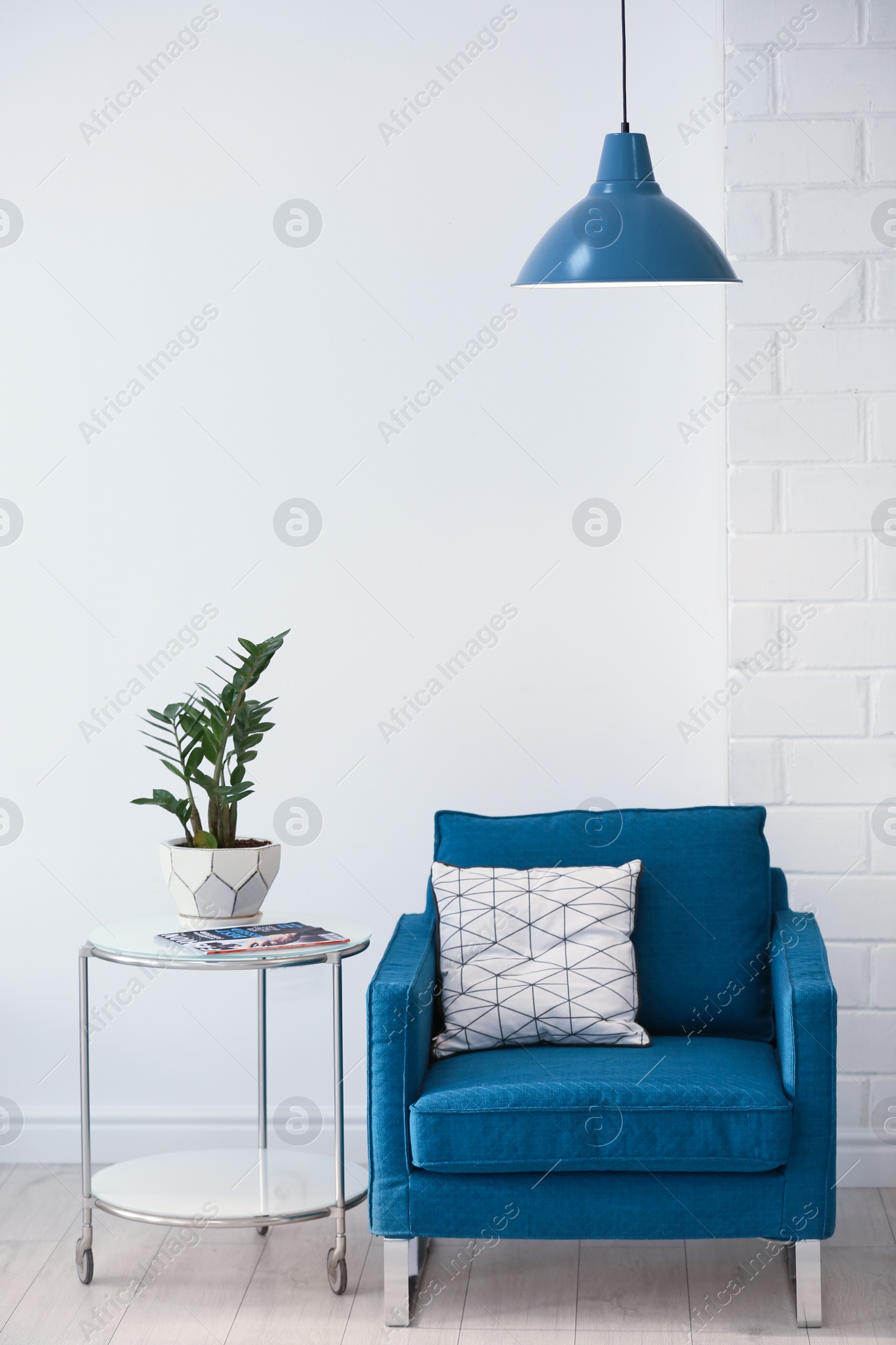 Photo of Modern lamp with plant on table and armchair indoors