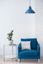 Modern lamp with plant on table and armchair indoors