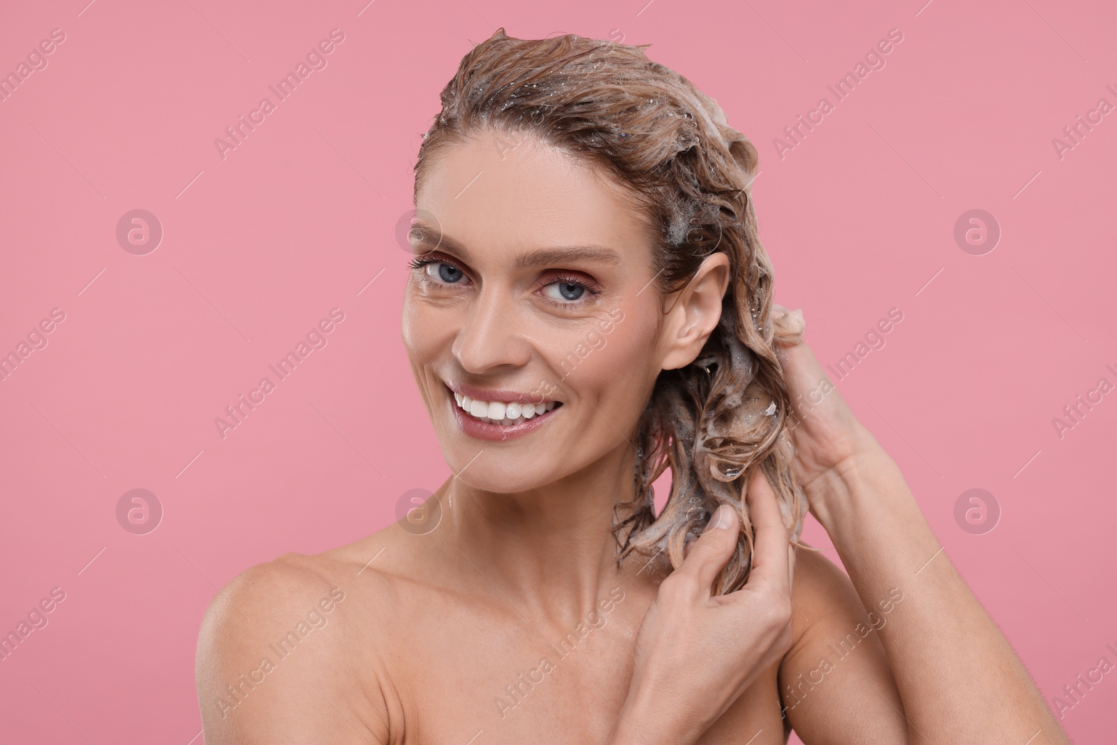 Photo of Beautiful happy woman washing hair on pink background