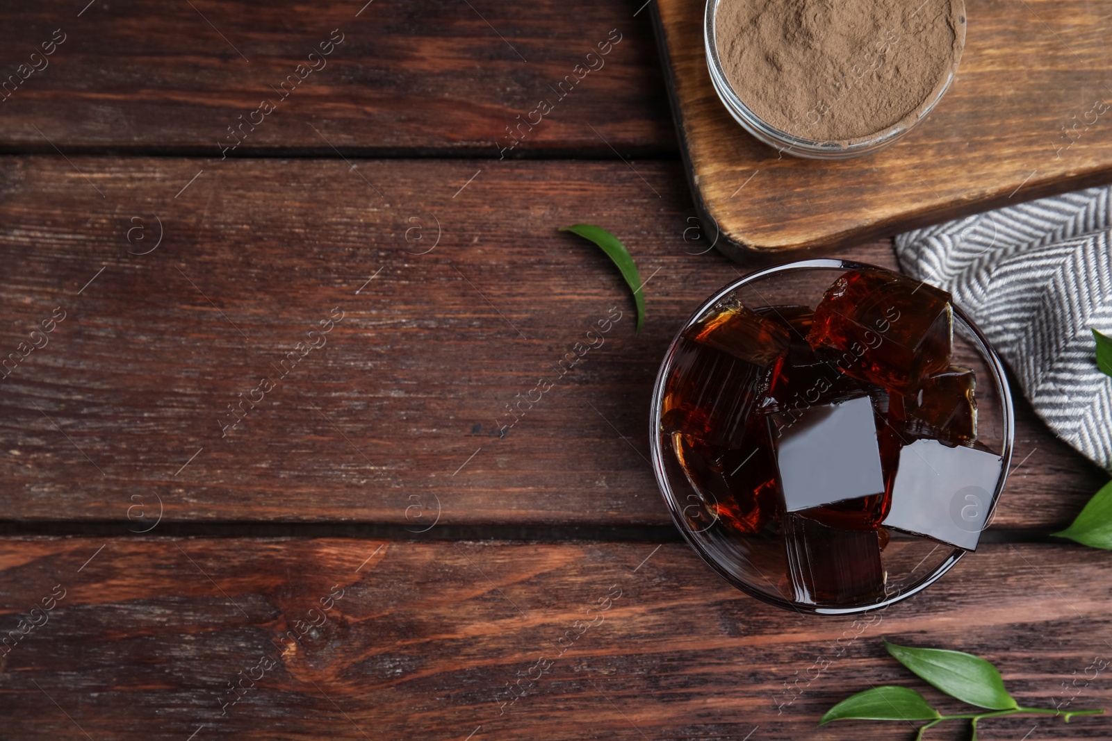 Photo of Delicious grass jelly cubes on wooden table, flat lay. Space for text