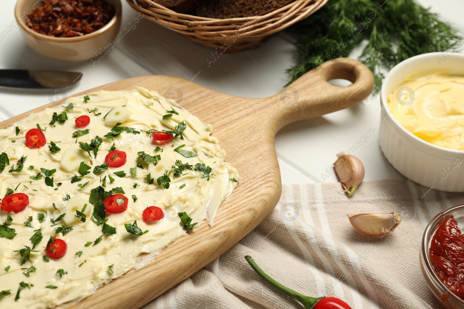 Photo of Fresh natural butter board with pepper and garlic on white wooden table